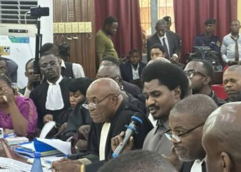 Tense courtroom scene in Kinshasa: Constant Mutamba, holding the microphone, addresses the judges and denounces alleged intimidation. Surrounded by his lawyers and a focused audience, the opposition leader declares: “I am not here to receive threats.