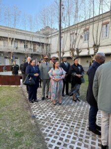 Une délégation congolaise en visite officielle, rassemblée dans la cour d’un bâtiment historique, marquant un moment solennel de mémoire et de diplomatie. Parmi les membres, des officiers supérieurs, des diplomates et des représentants civils, unis dans un esprit de recueillement et de coopération internationale